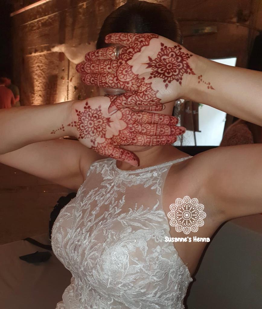 Braut im weissen Kleid zeigt ihre mit Henna verzierten Handflächen