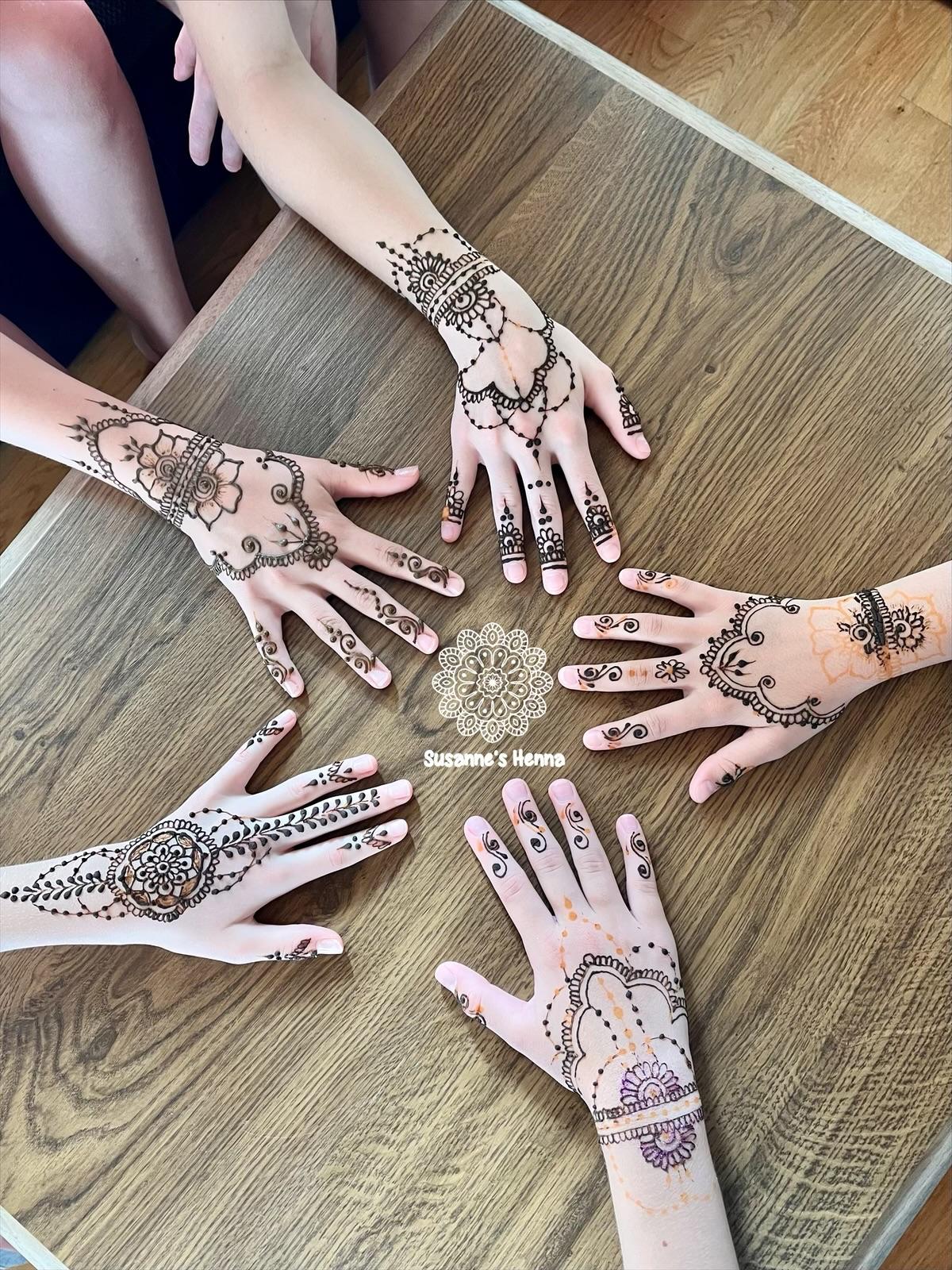 Mehrere Hände mit frischem Henna nebeneinander