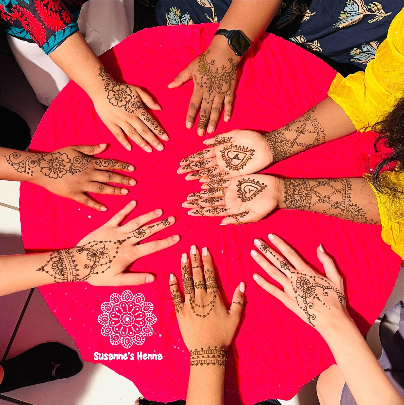 Viele Hände mit Henna-Designs im Kreis bei einem Gruppenanlass